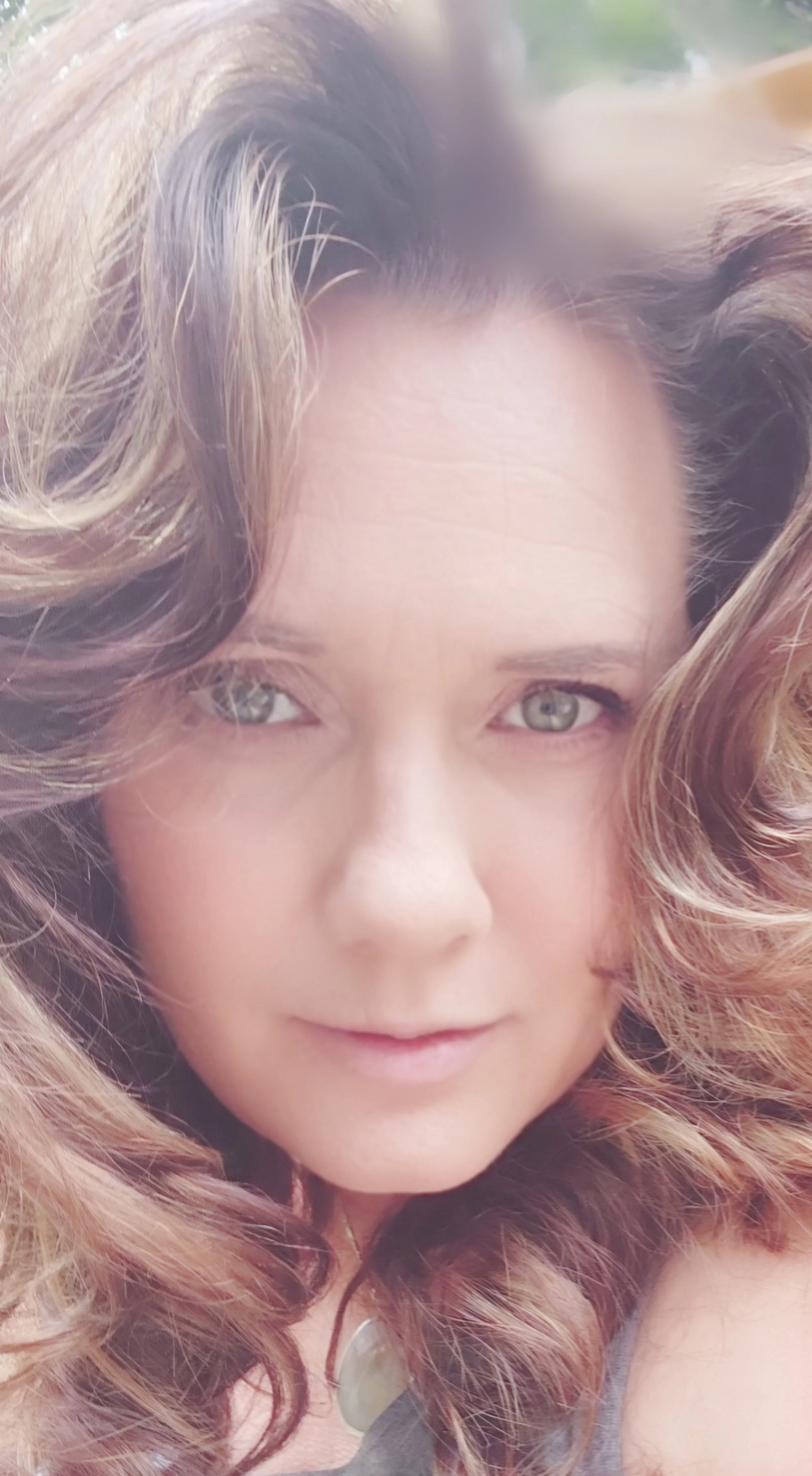 Close-up facial picture of Irma Schuur. She has wavy, light brown hair with blonde highlights and light green-colored eyes.