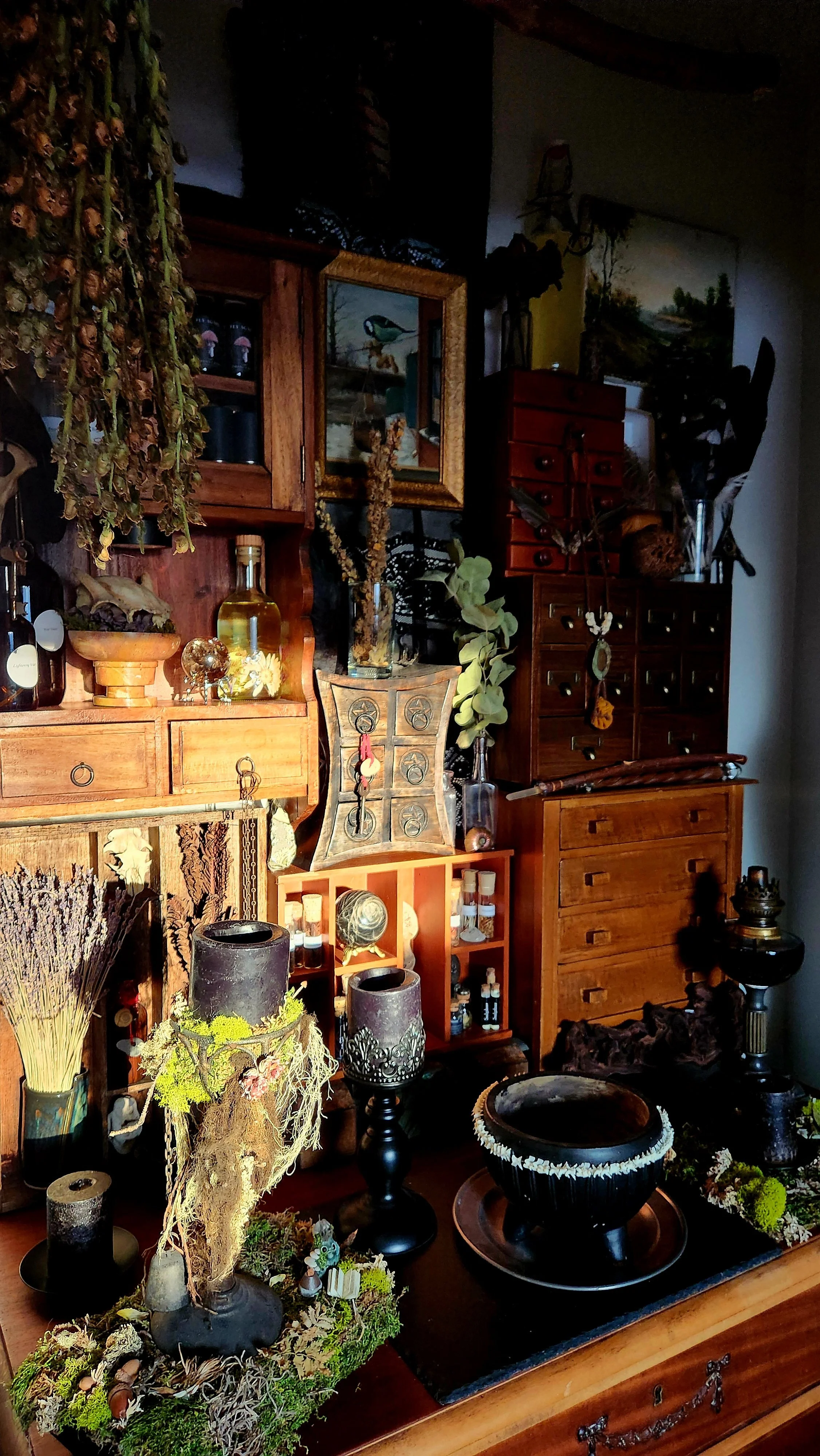A collection of wooden furniture, decorative items, and plants arranged on and around a wooden dresser in a cozy interior.
