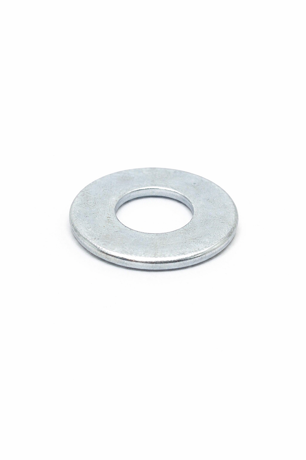 A metal washer with a circular hole in the center, placed on a white background.