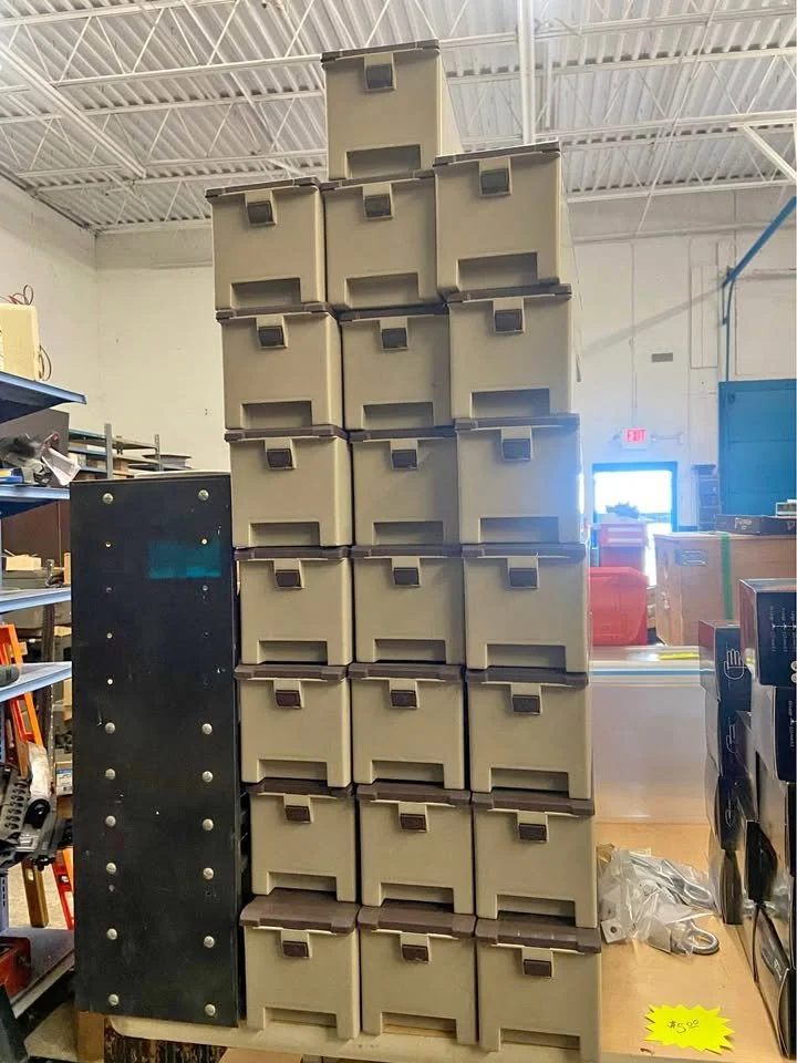 A tall stack of beige storage bins with brown handles in what appears to be a warehouse or store.
