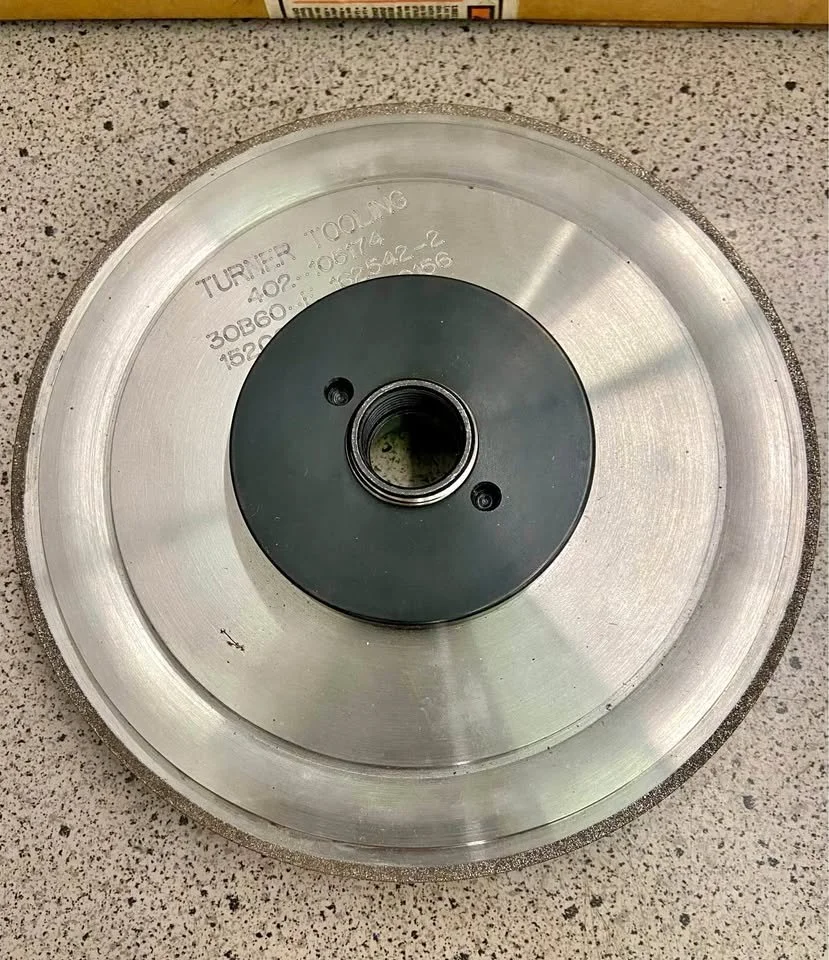 Metal grinding or cutting wheel on a speckled gray surface, with some text engraved on it.