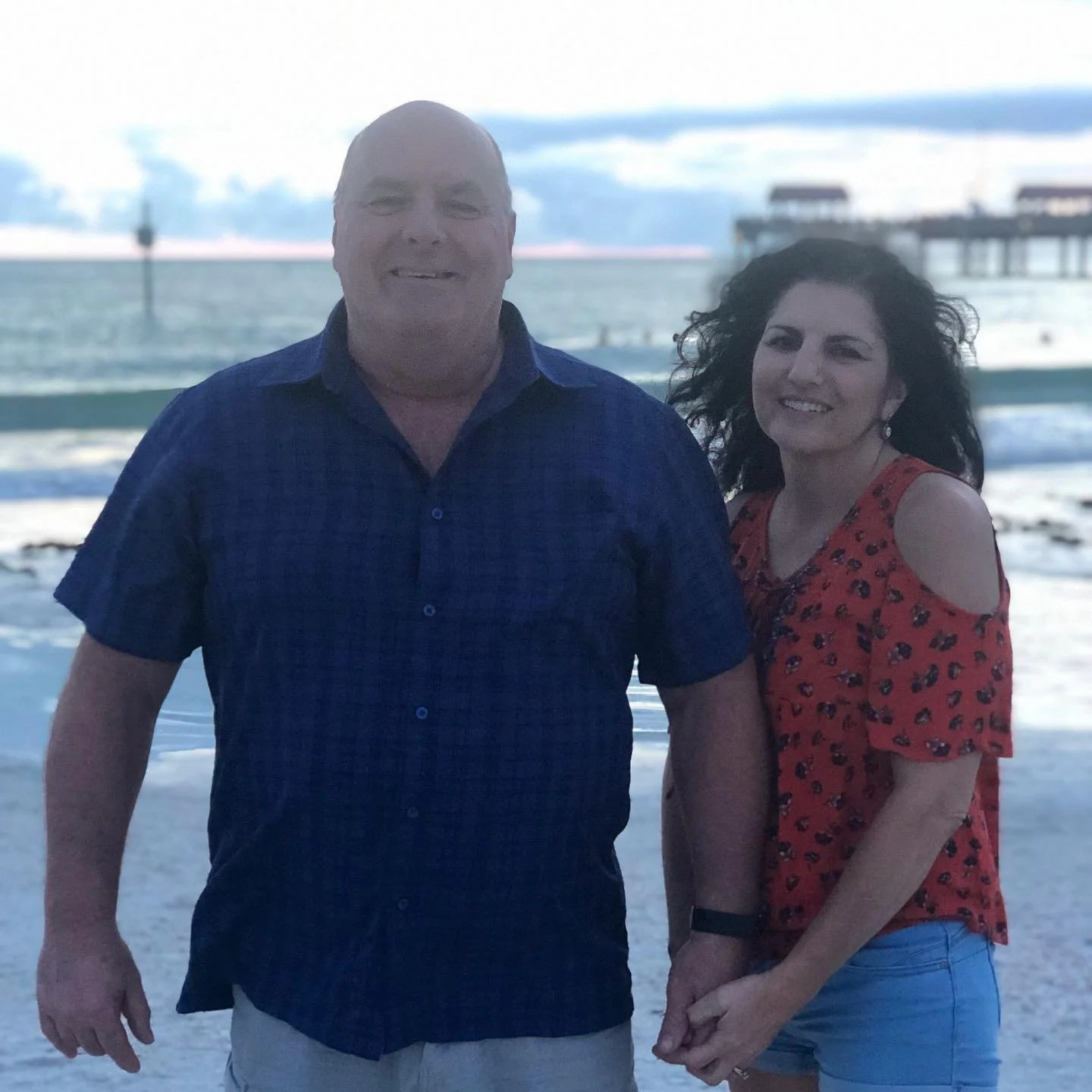 Owners of Mikron Fasteners smiling together, based in Mentor, Ohio, with a pier and water in the background