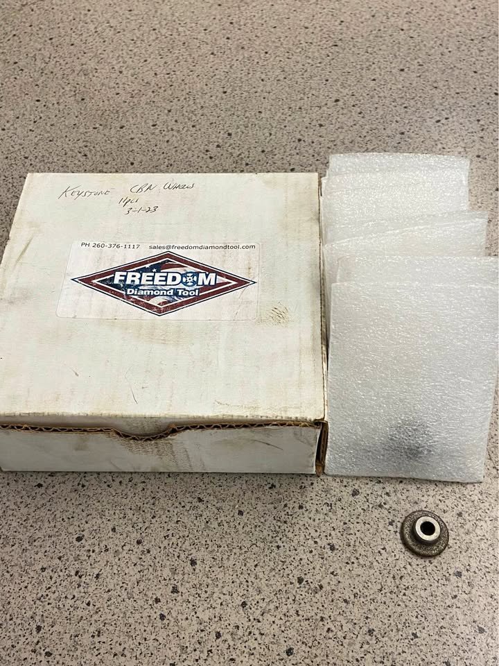 A white box with the Freedom Diamond Tool logo and contact information, next to a piece of foam padding and a small metallic part on a speckled countertop.