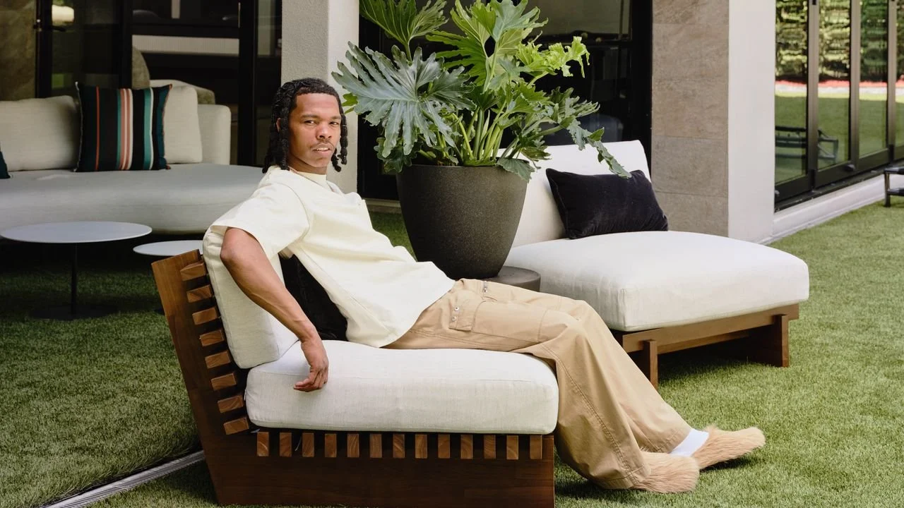 Man lounging on outdoor furniture with large potted plant nearby in a modern backyard patio.