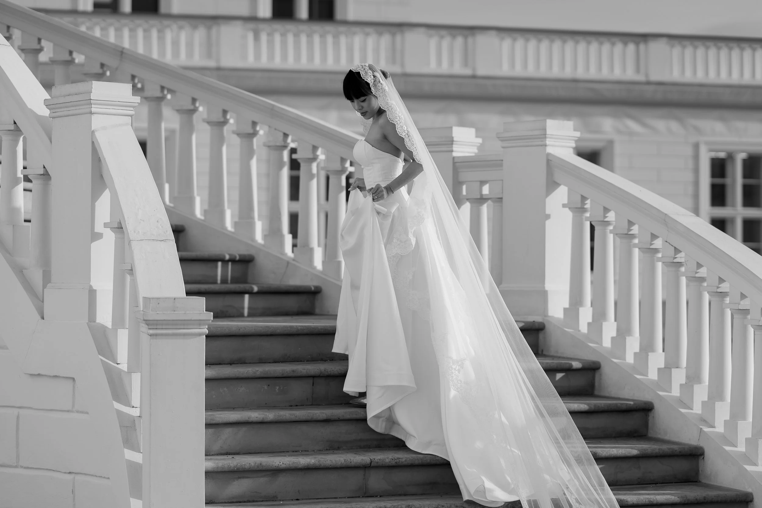 Braut in Brautkleid mit Schleier steigt die Treppe eines historischen Gebäudes.