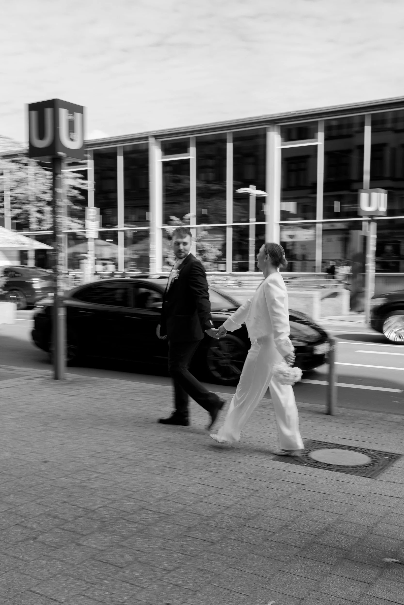 Ein Mann und eine Frau gehen zusammen auf der Straße, wahrscheinlich bei einer Hochzeit, bei der Frau trägt ein weißes Hochzeitskleid.