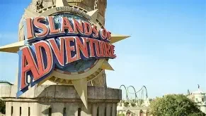 Sign for Islands of Adventure theme park with roller coasters in the background.