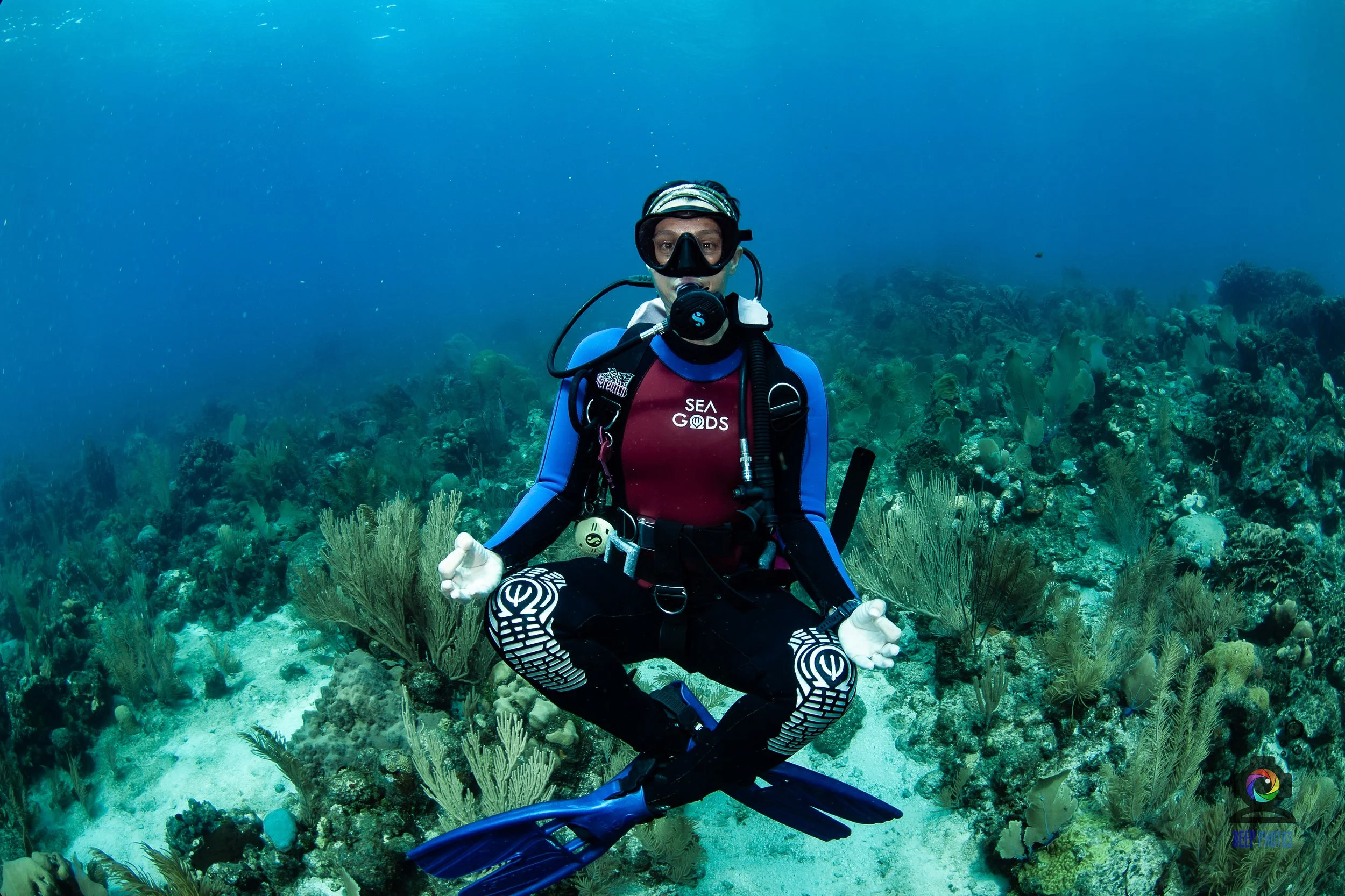 A scuba diver in full gear underwater surrounded by a vibrant coral reef.