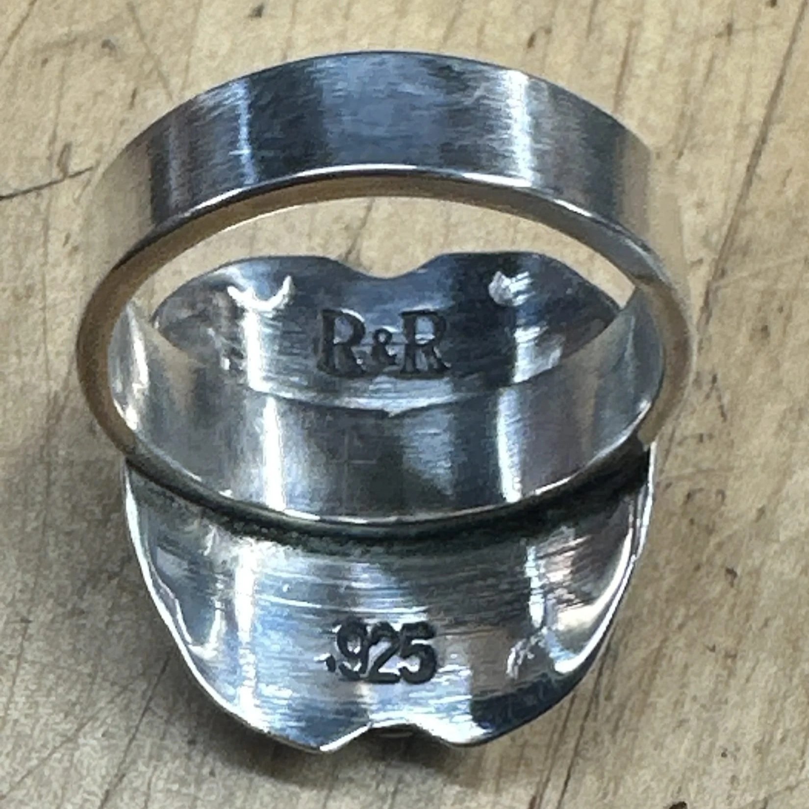 Back of a sterling silver shield ring stamped R&R and .925