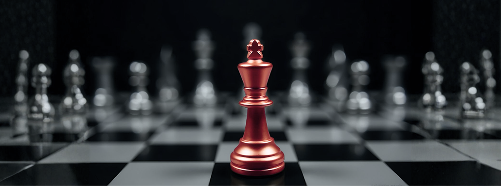 A red king chess piece on a chessboard with other pieces blurred in the background.