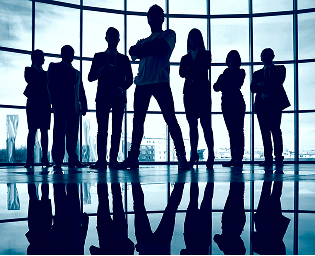 Silhouettes of seven business professionals standing confidently in front of large windows in a modern office building.