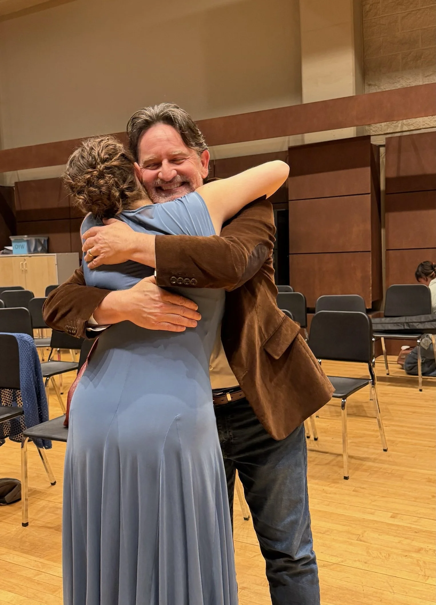 A man happily hugging a woman in a light blue dress.