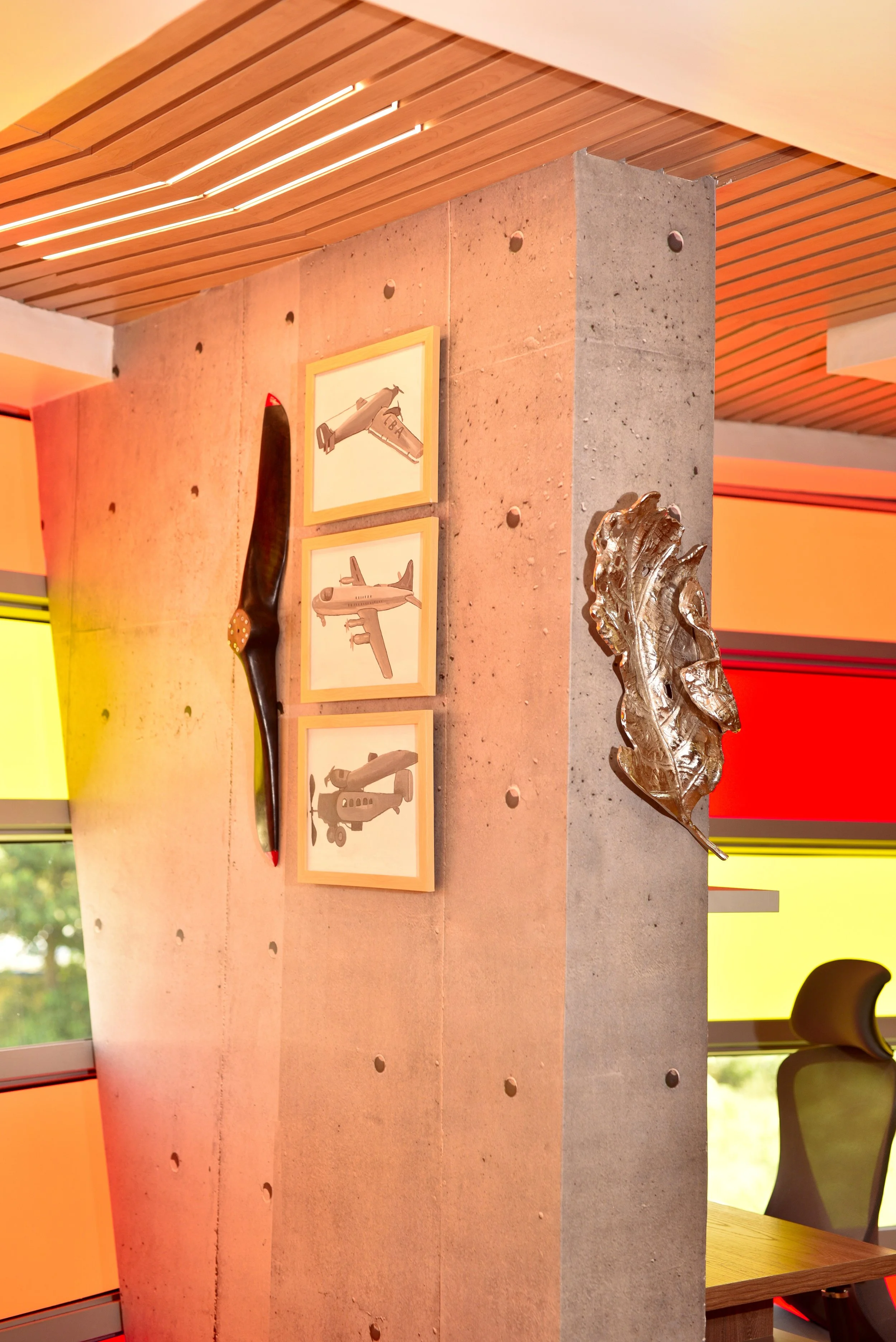 Warm wooden ceiling treatment and textured structural column designed to create a calming atmosphere within a high-performance corporate lounge.