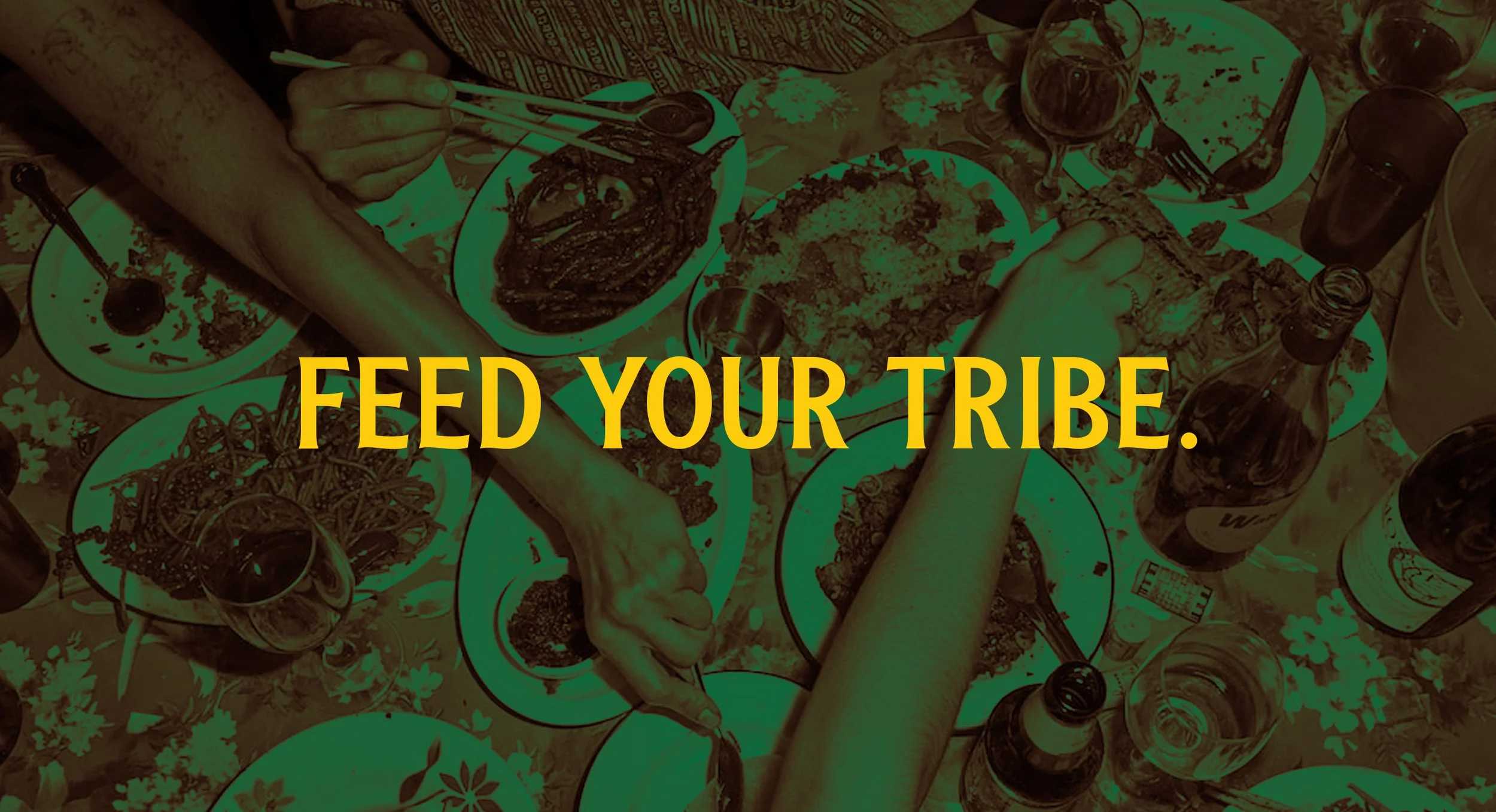 A table of multiple plates with various foods, beverages, and utensils, with the text overlay 'Feed Your Tribe' in yellow.