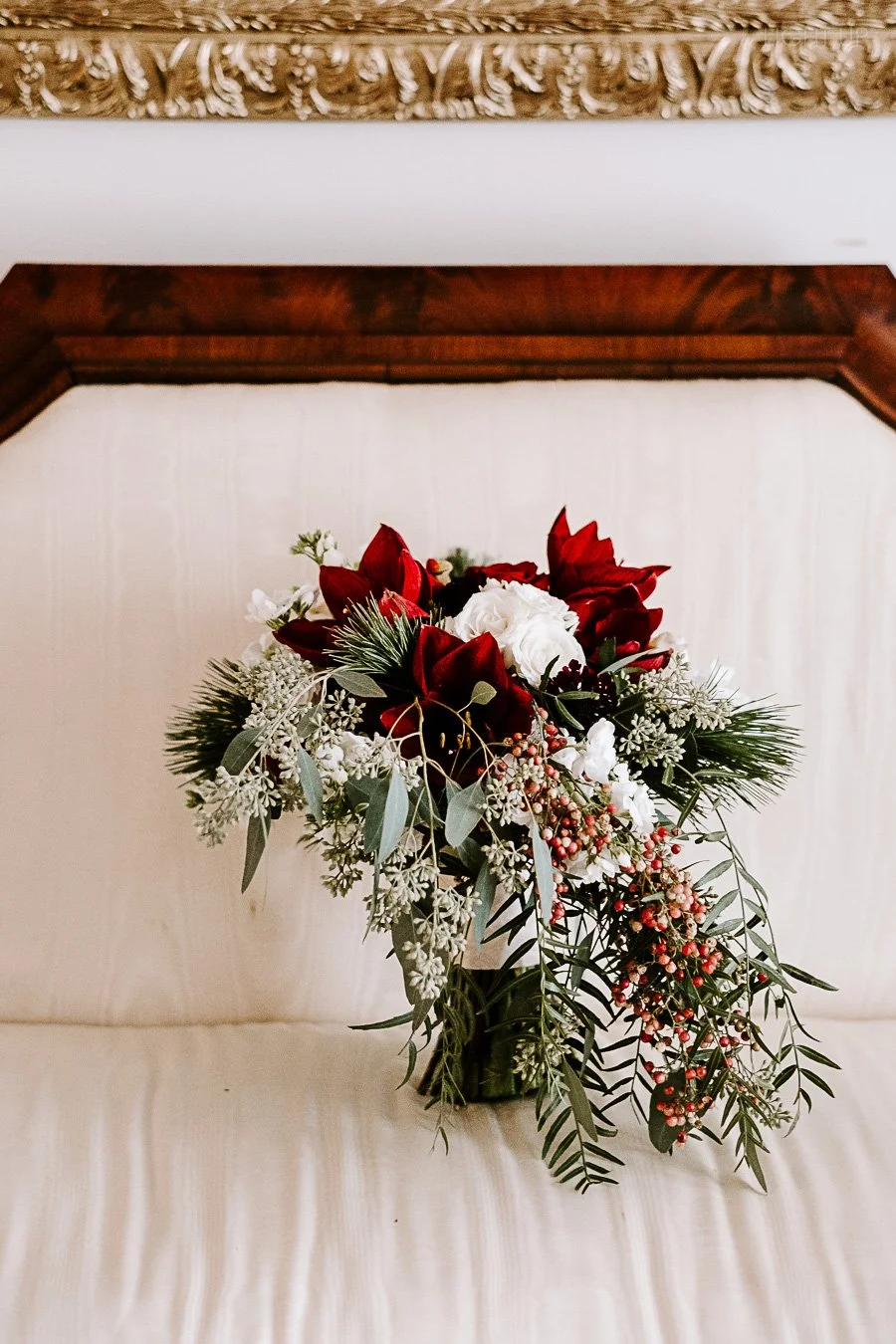 Bridal bouquet with red, white, and green flowers and foliage.