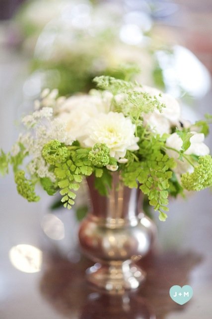 White and green floral arrangement in a silver vase.