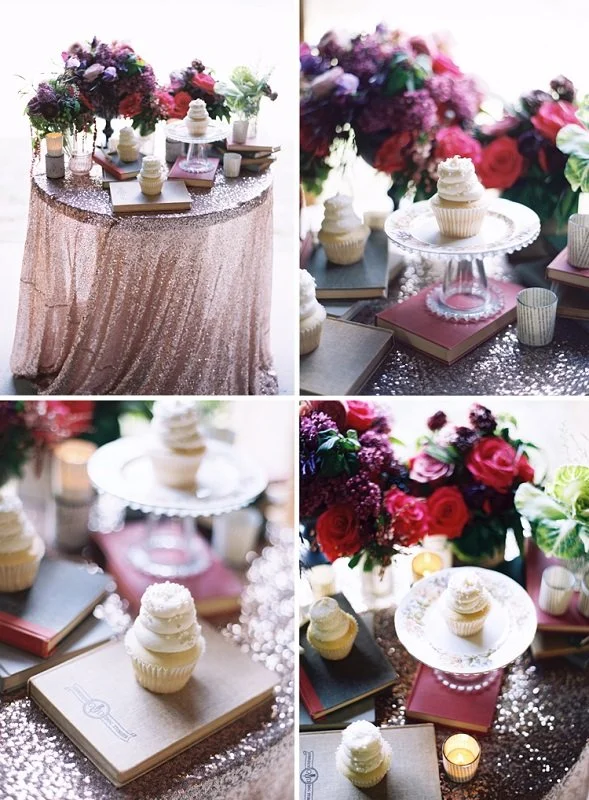 A table decorated with flowers, cupcakes, books, and candles