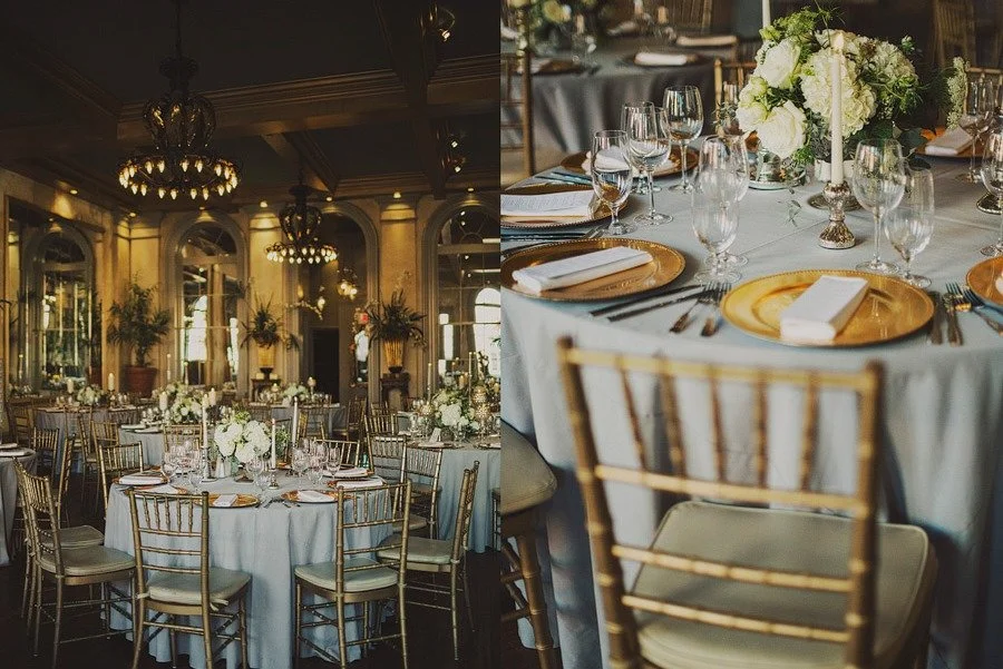 Elegant banquet hall with round tables decorated with white tablecloths, floral centerpieces, and gold chairs; one table set with gold plates, white napkins, and glassware, in a luxurious setting with chandeliers and large windows.