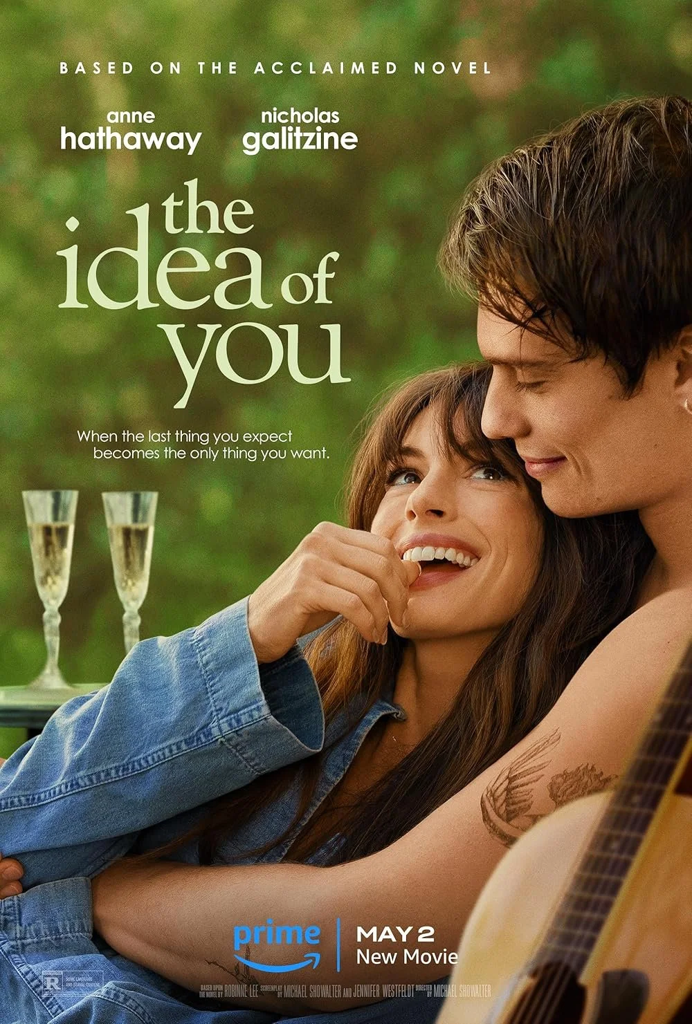 Poster for the movie "The Idea of You" featuring a woman and a man smiling and embracing outdoors with a green background. Two glasses of champagne are visible in the background.