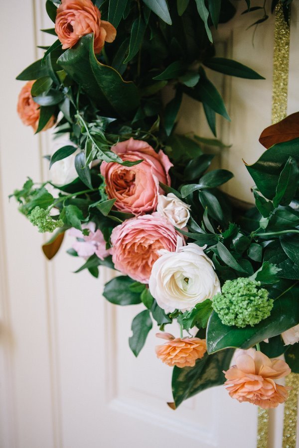 A floral arrangement featuring various pink, white, and peach flowers with green leaves and foliage.