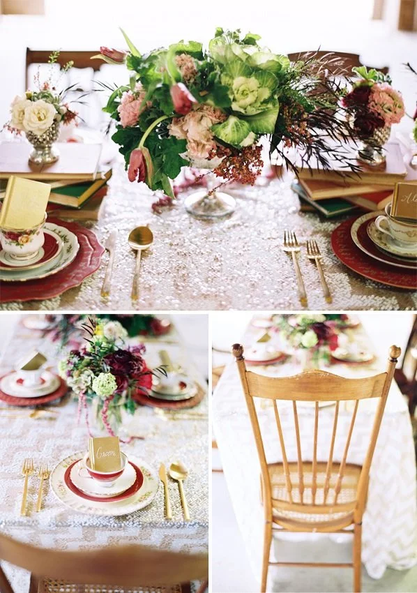 A decorated dining table with a floral centerpiece, gold cutlery, and elegant dishware, set for a formal meal, with wooden chairs and a lace tablecloth.