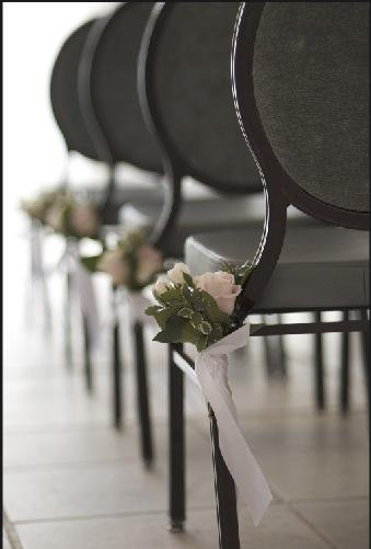 Chairs decorated with flowers and ribbons, likely prepared for a wedding or special event.