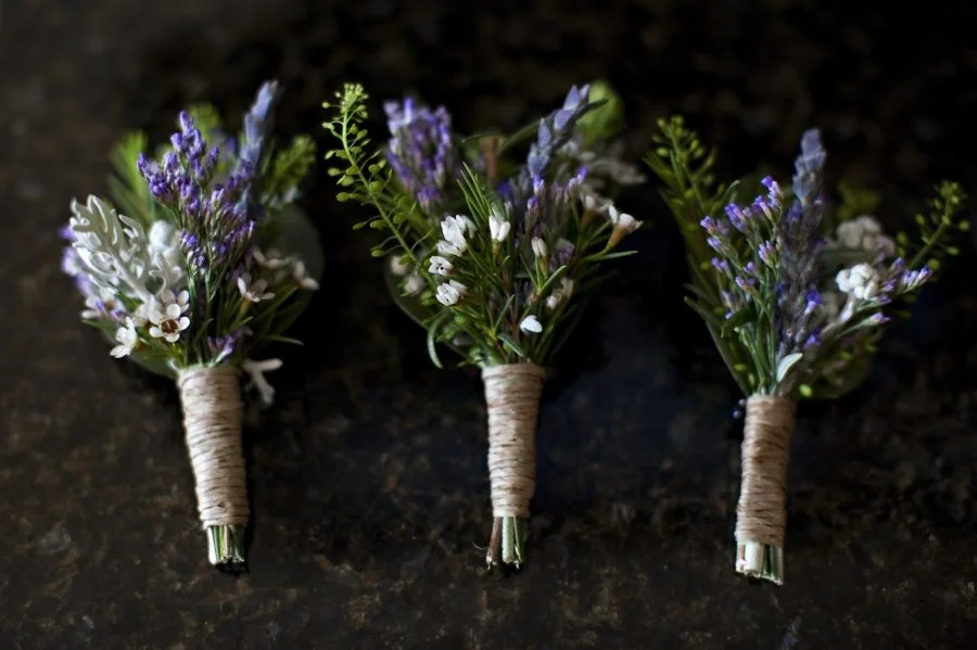 Three small bouquets of lavender and white flowers wrapped with twine, placed on a dark surface.