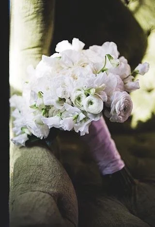 A person holding a bouquet of white flowers and roses.