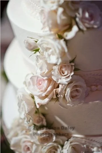 Close-up of a wedding cake decorated with white and blush pink roses.