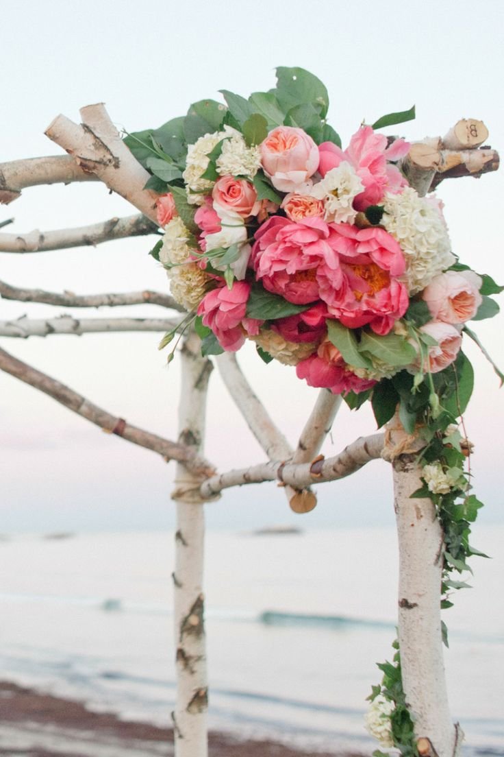 Flower arrangement with pink and white flowers on a rustic wooden arch at the beach