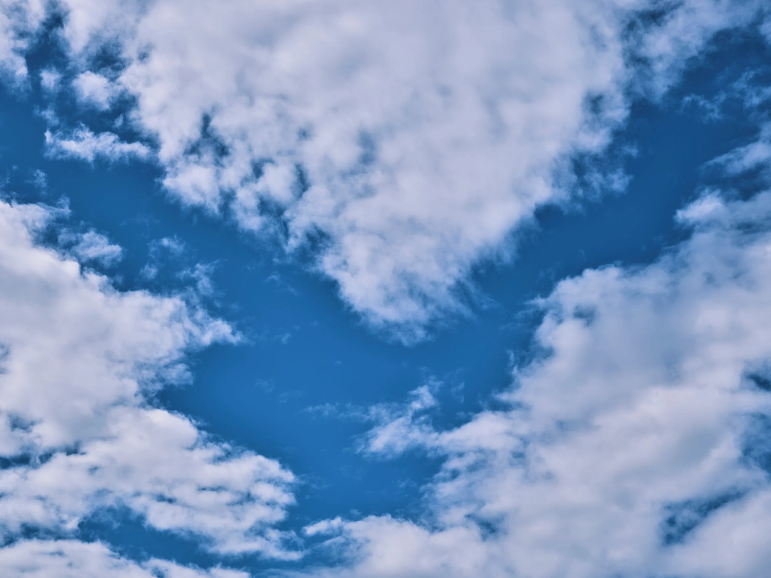 Blue sky with fluffy white clouds drifting across a bright daytime atmosphere