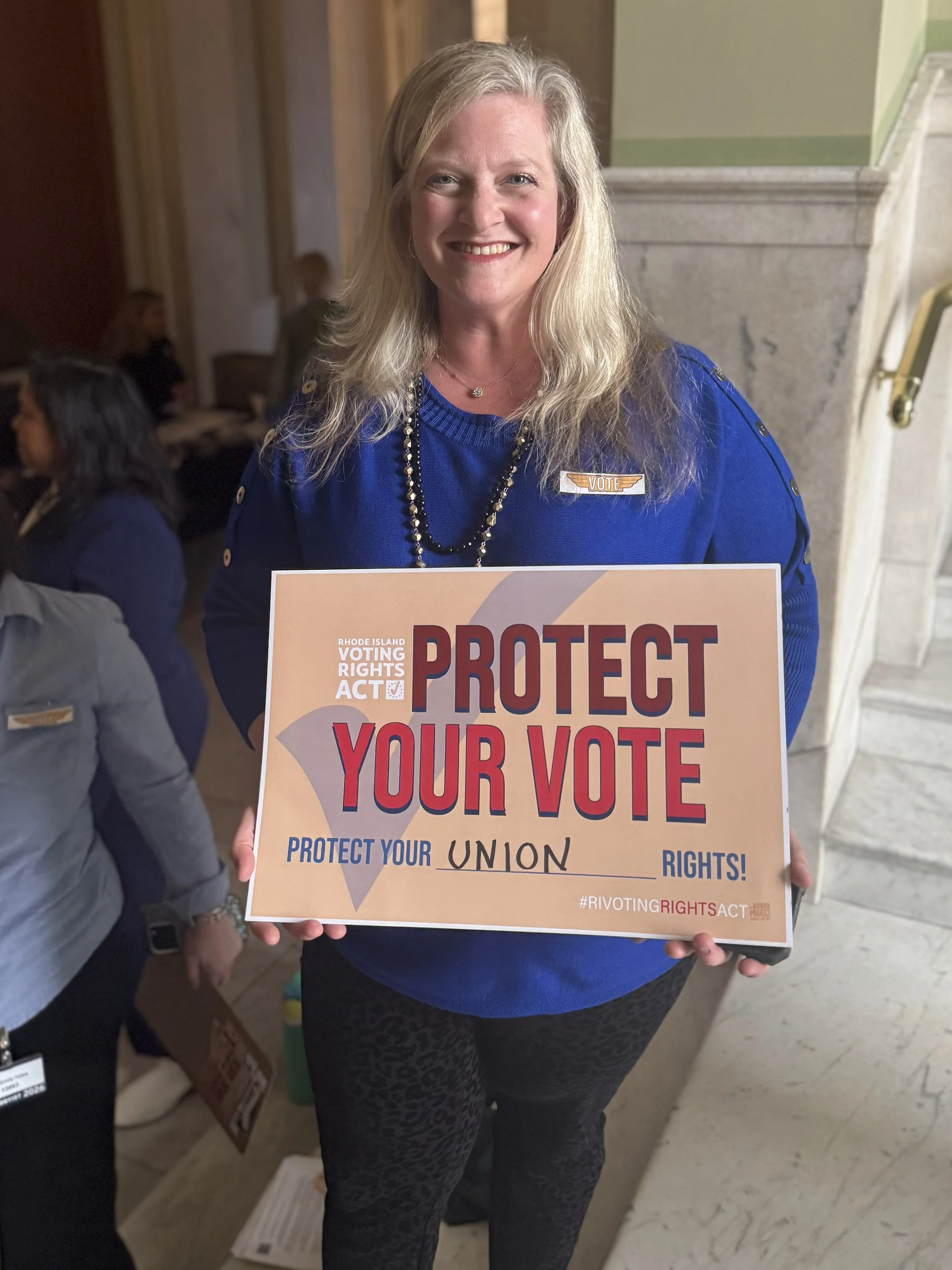 Supporter holds sign saying "Protect Your Vote and Union Rights"