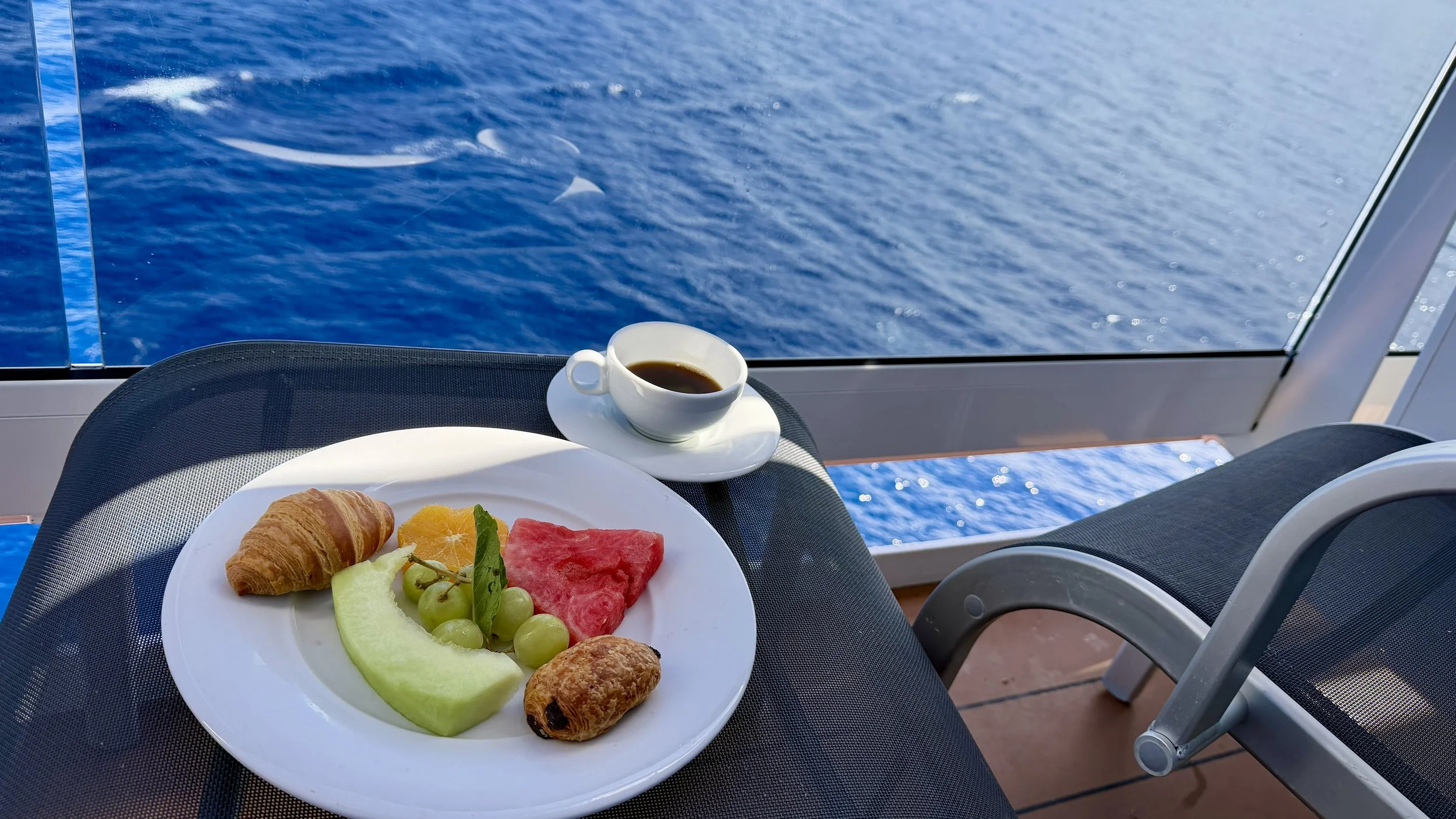 Fruit and pastries and coffee on MSC cruise ship balcony with ocean in background