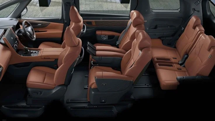 Interior of a vehicle showing two rows of brown leather seats, with the front seats turned slightly to view the second row.