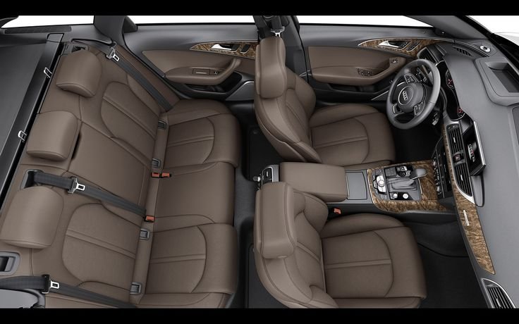 Interior of a luxury car, showing brown leather seats, dashboard, steering wheel, and wood trim on the center console and door panels.