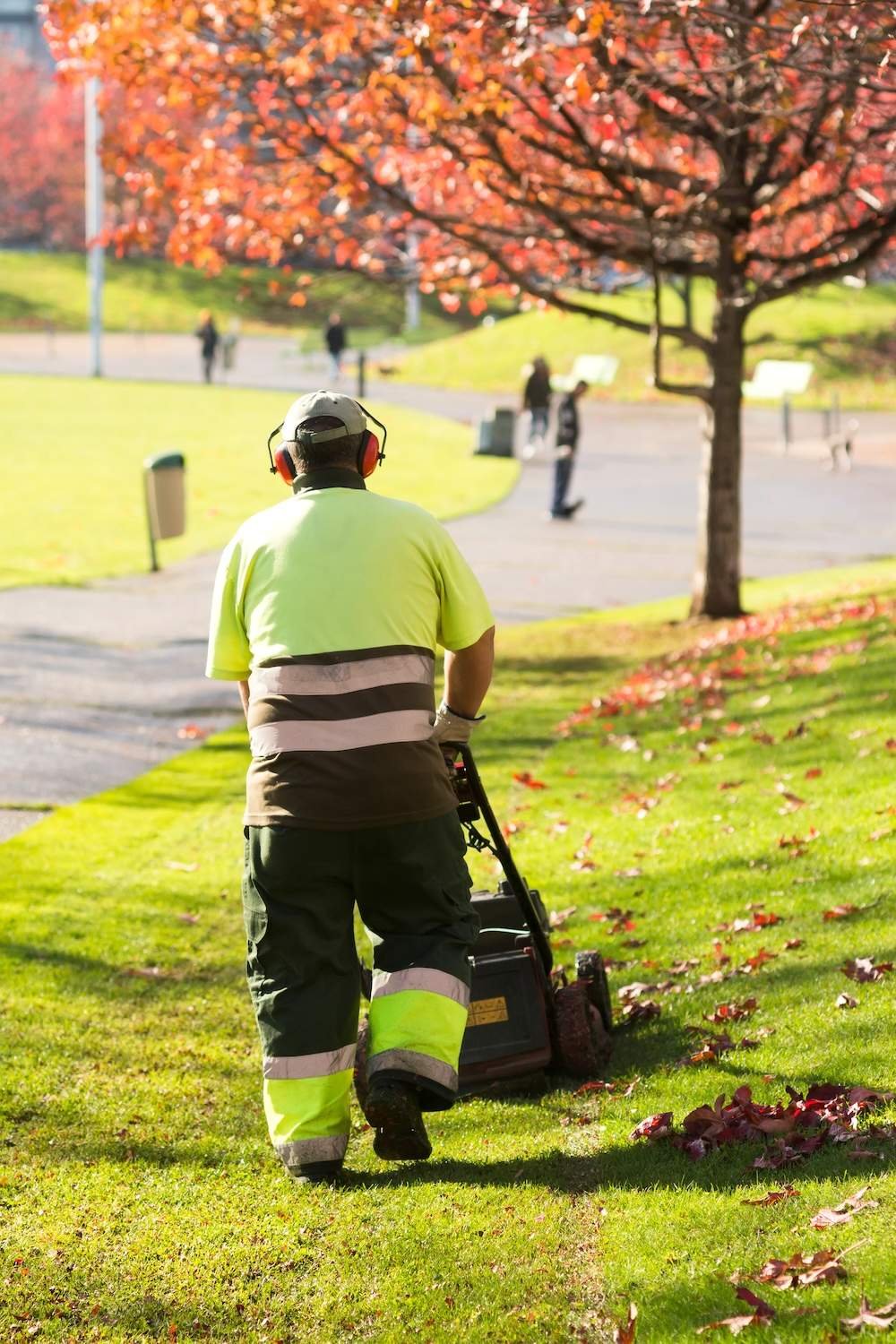 A landscaper mowing a public lawn in an HOA community
