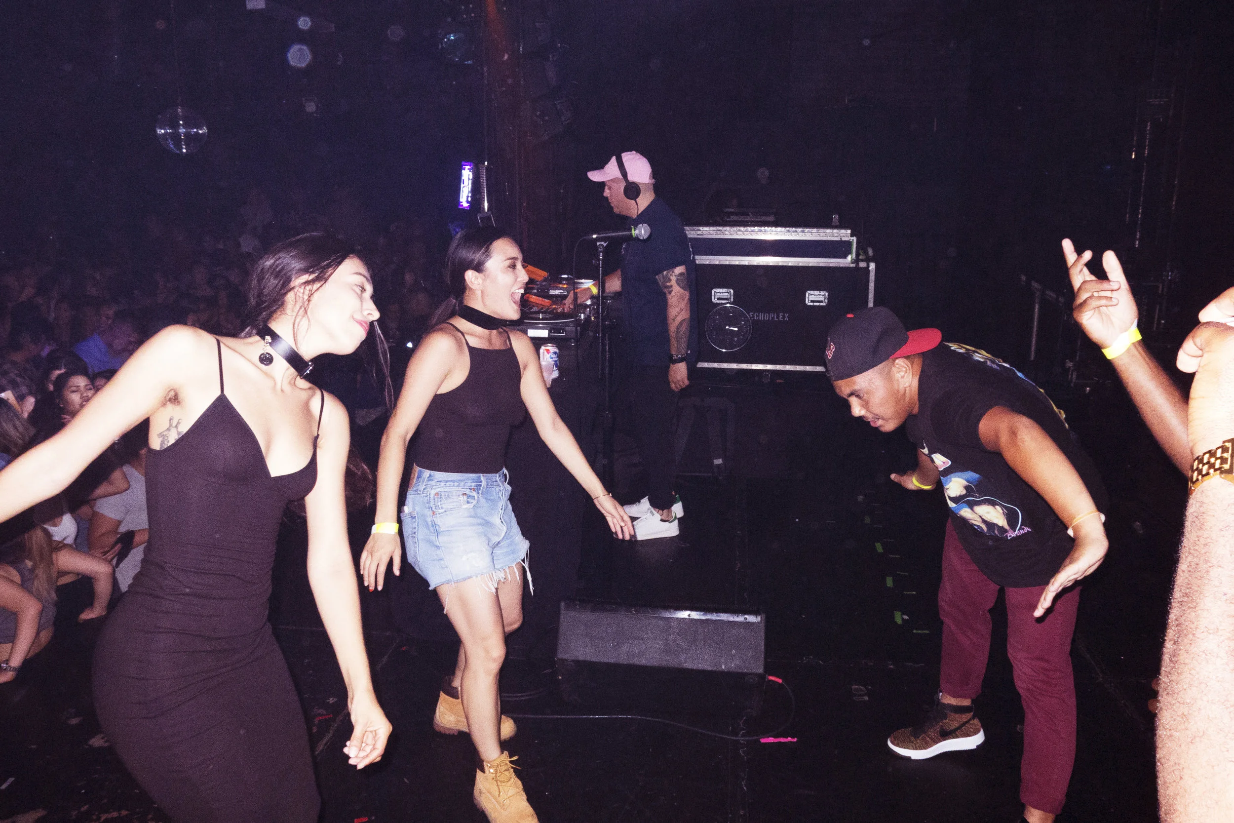 People dancing and enjoying music at a nightclub, with a DJ in the background.