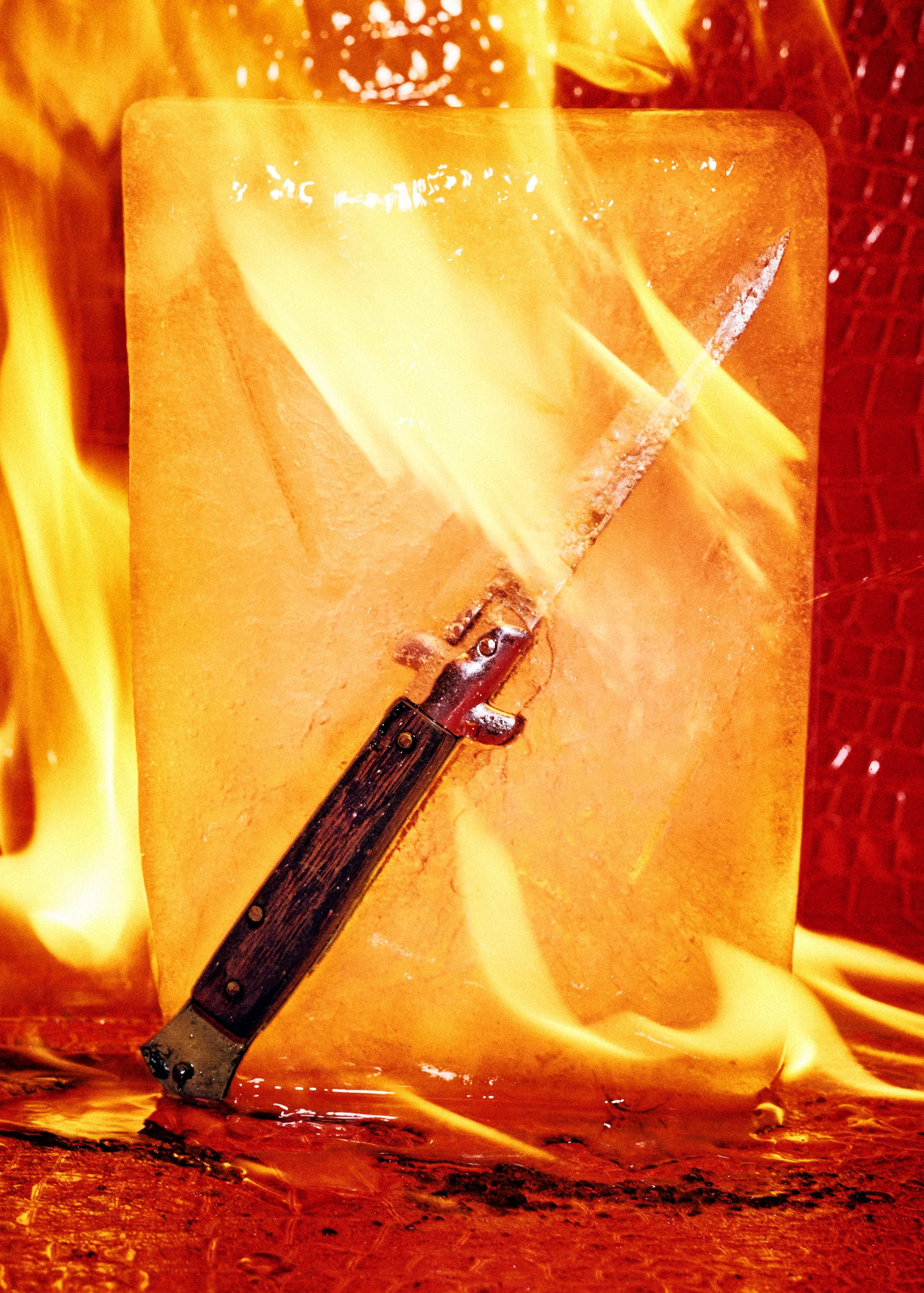 A large block of melting yellow-orange cheese with a knife inserted into it, with flames and melted cheese around it.