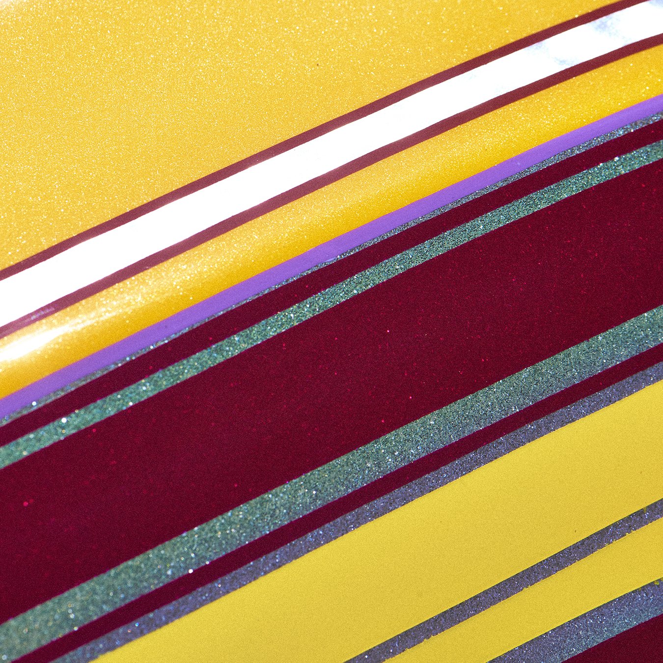 Close-up of colorful, glittery diagonal stripes in yellow, red, purple, green, and blue.