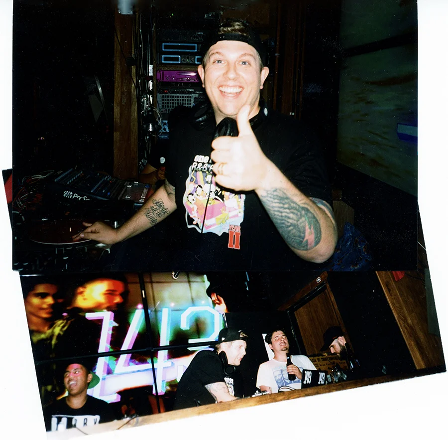 Man smiling and giving a thumbs-up with DJ equipment behind him, and a screen showing a digital clock and people in the background.