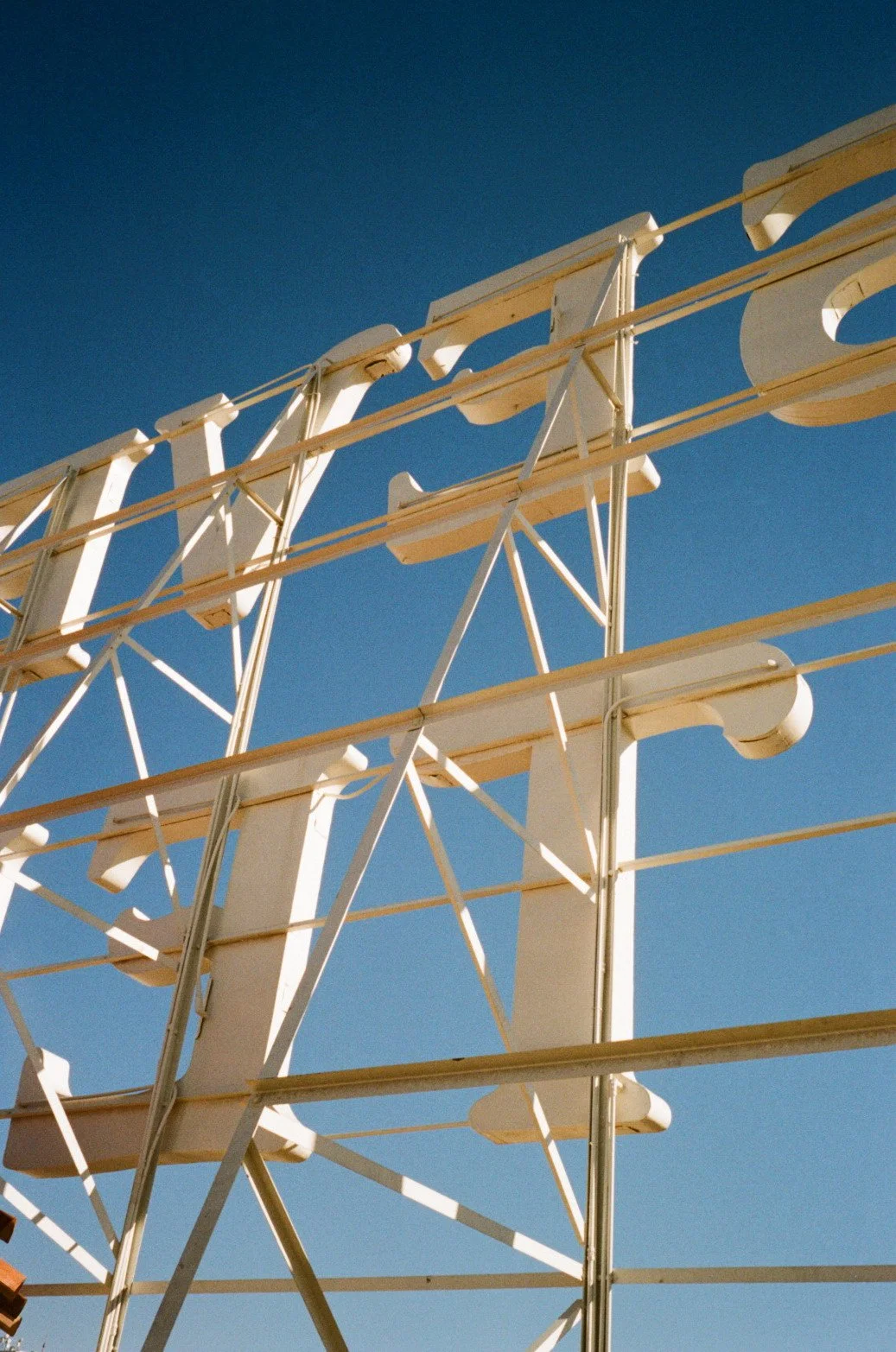 Close-up view of a vintage Ferris wheel with a white structure against a clear blue sky.