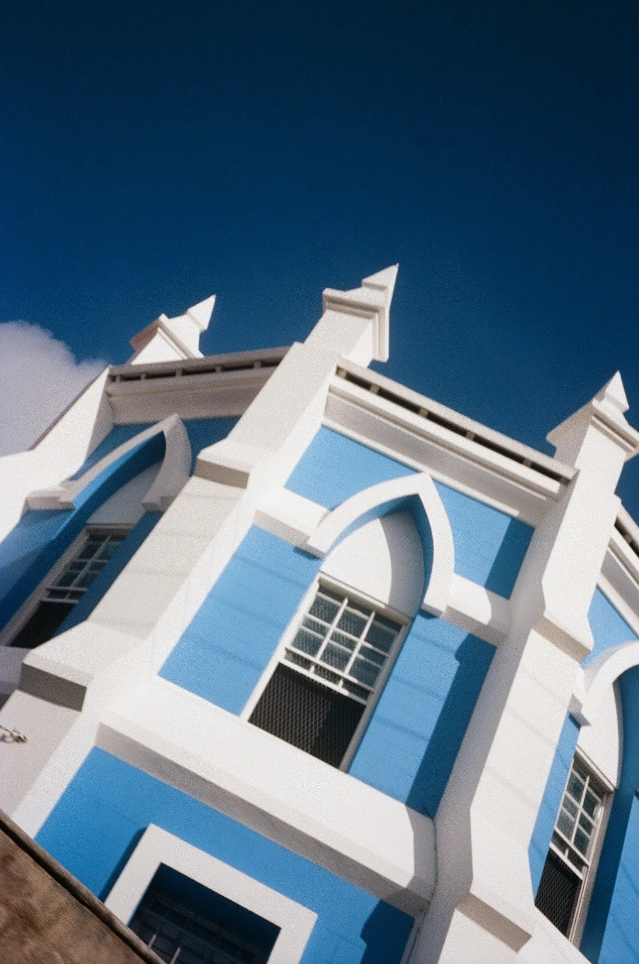 Close-up view of a blue and white building with ornate architectural details, set against a blue sky with a few clouds.