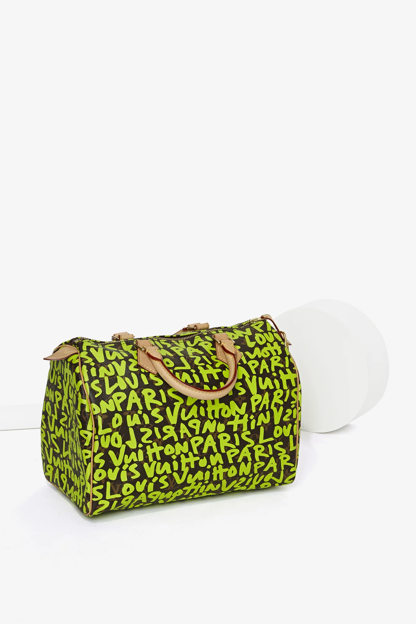 A green Louis Vuitton Louis Vuitton Paris designer bag with tan handles and accents, featuring a graffiti-style pattern of the brand's name.