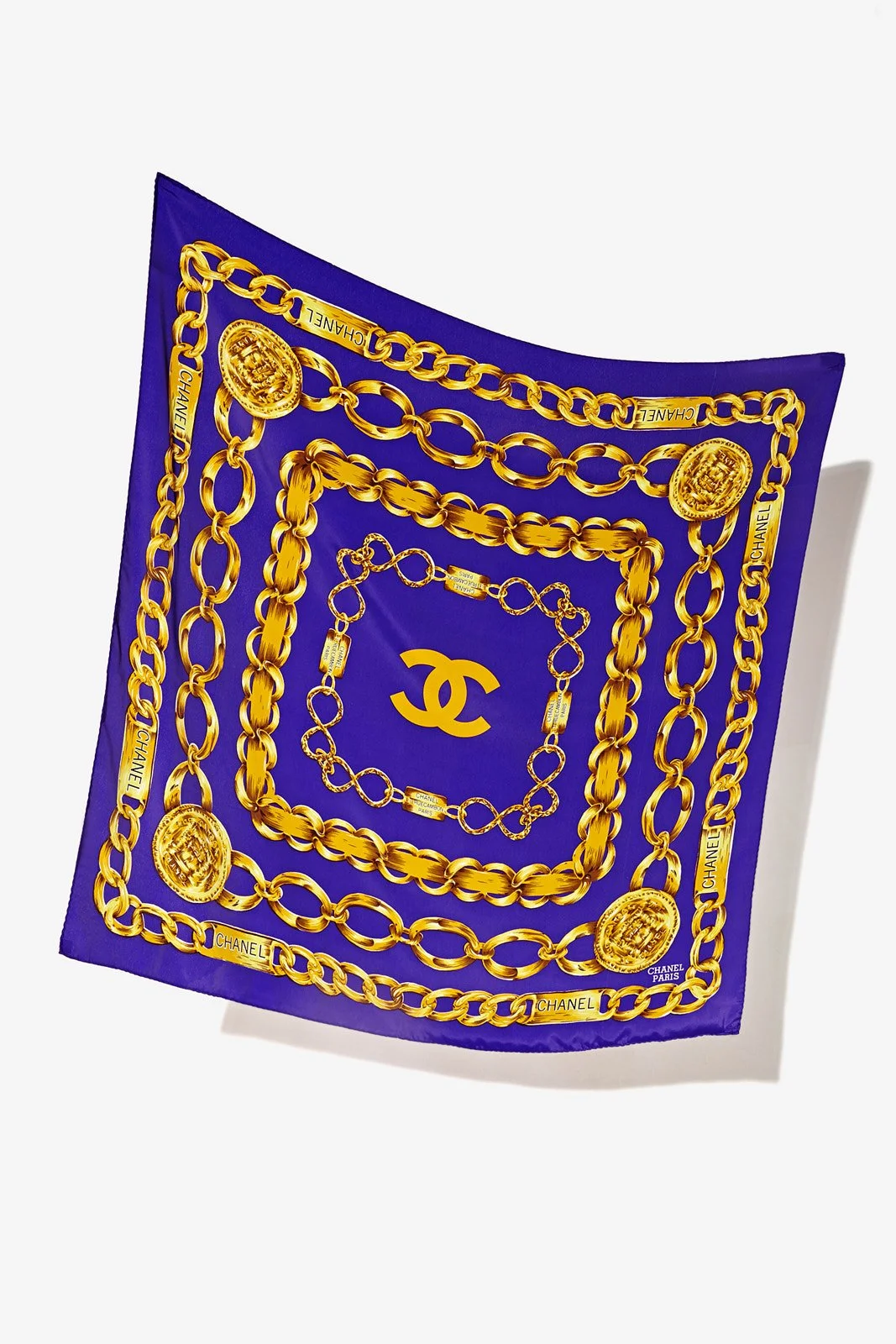 A blue fashion scarf decorated with gold chains, medallions, and the Chanel logo.