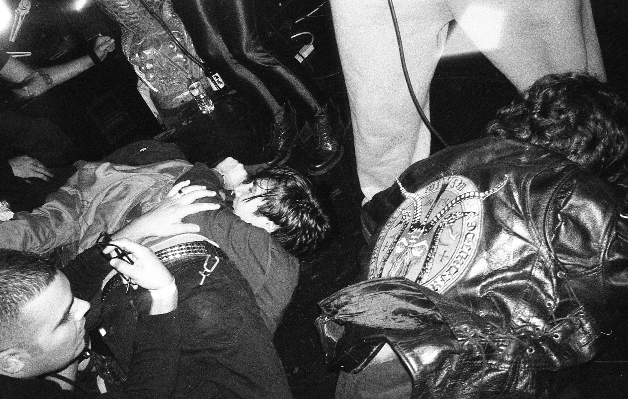 A group of young people appear to be resting or unconscious inside a vehicle, with some sitting or lying on the floor and others leaning against the seats. The photo is in black and white.