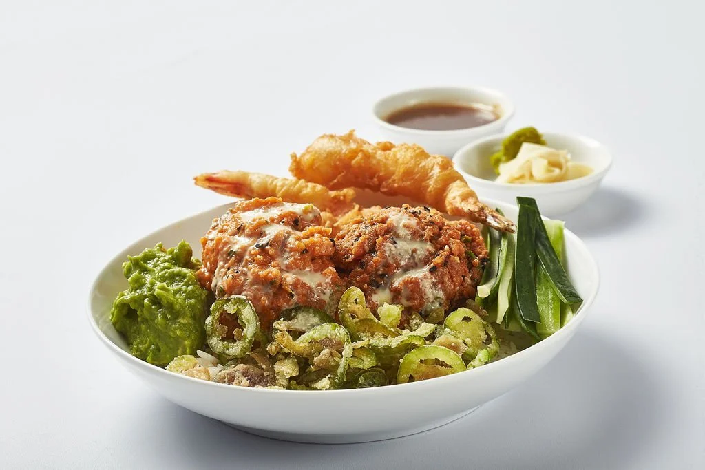 Bowl of Japanese food with fried shrimp, chicken meatballs, sliced cucumbers, green onions, wasabi, pickled ginger, soy sauce, and dipping sauces.