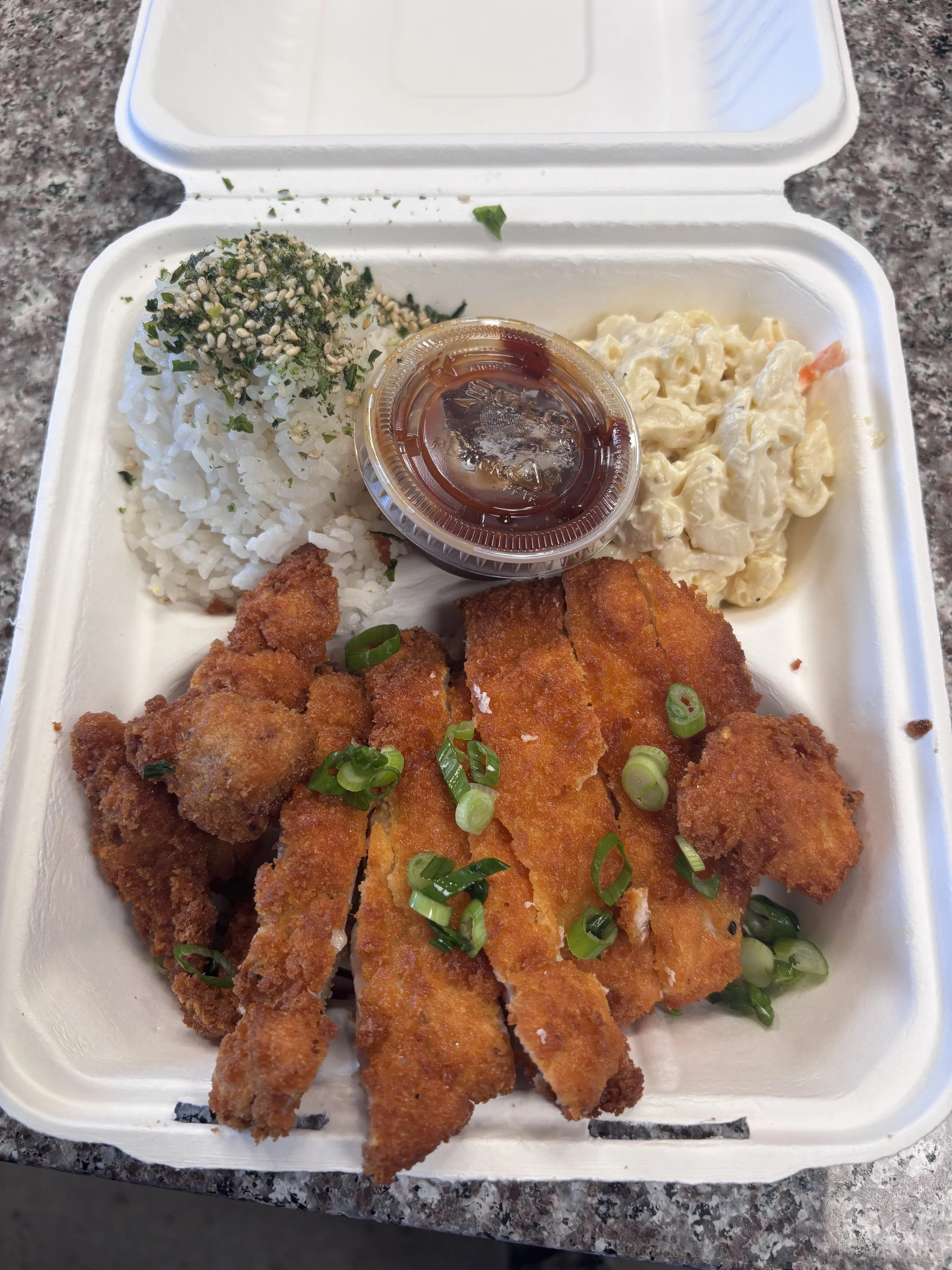Crispy chicken katsu with chopped green onions, white rice with furikake seasoning, macaroni salad, and a small cup of katsu sauce.
