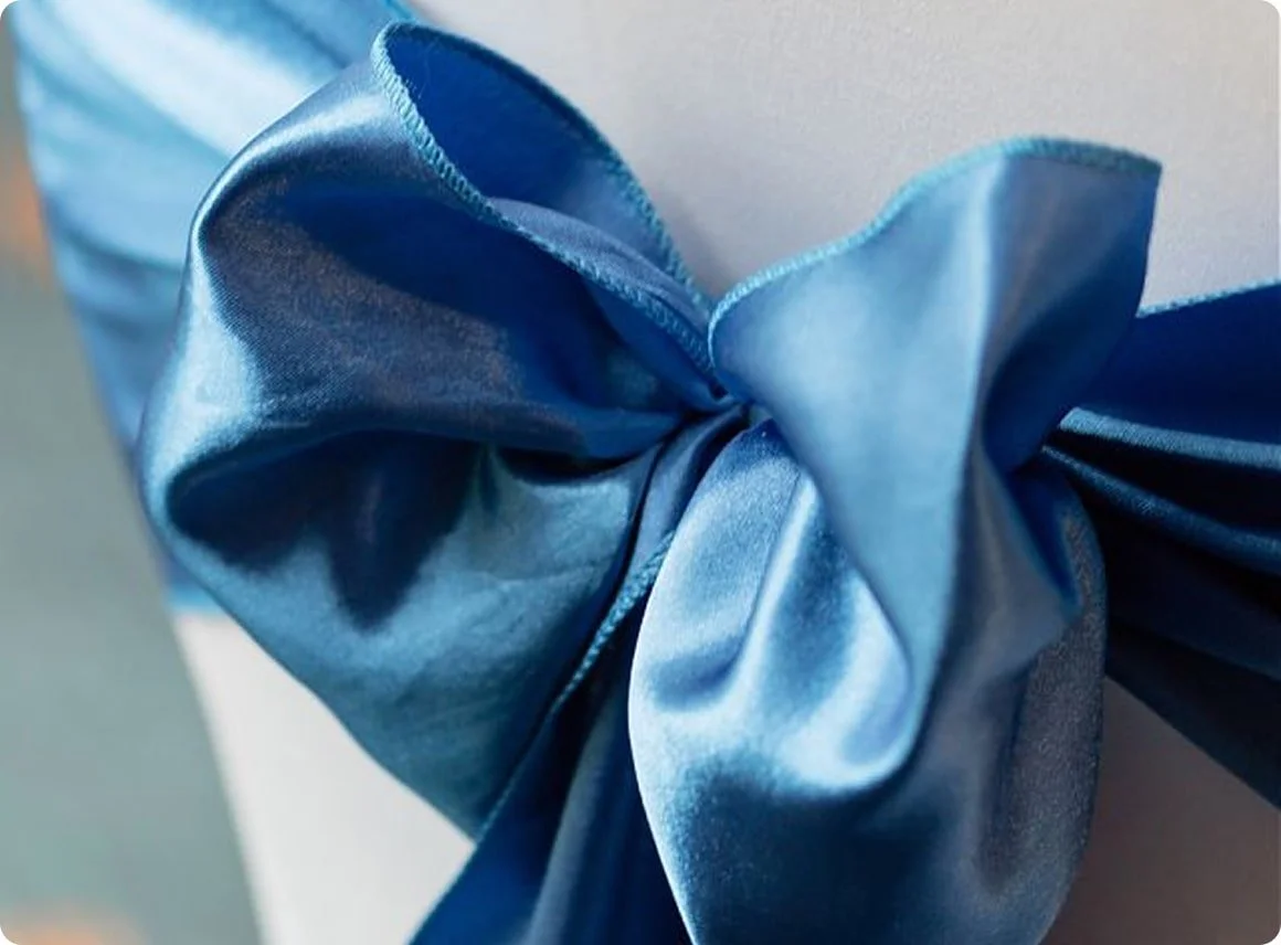 Close-up of a wrapped gift with a shiny blue satin ribbon tied in a bow.
