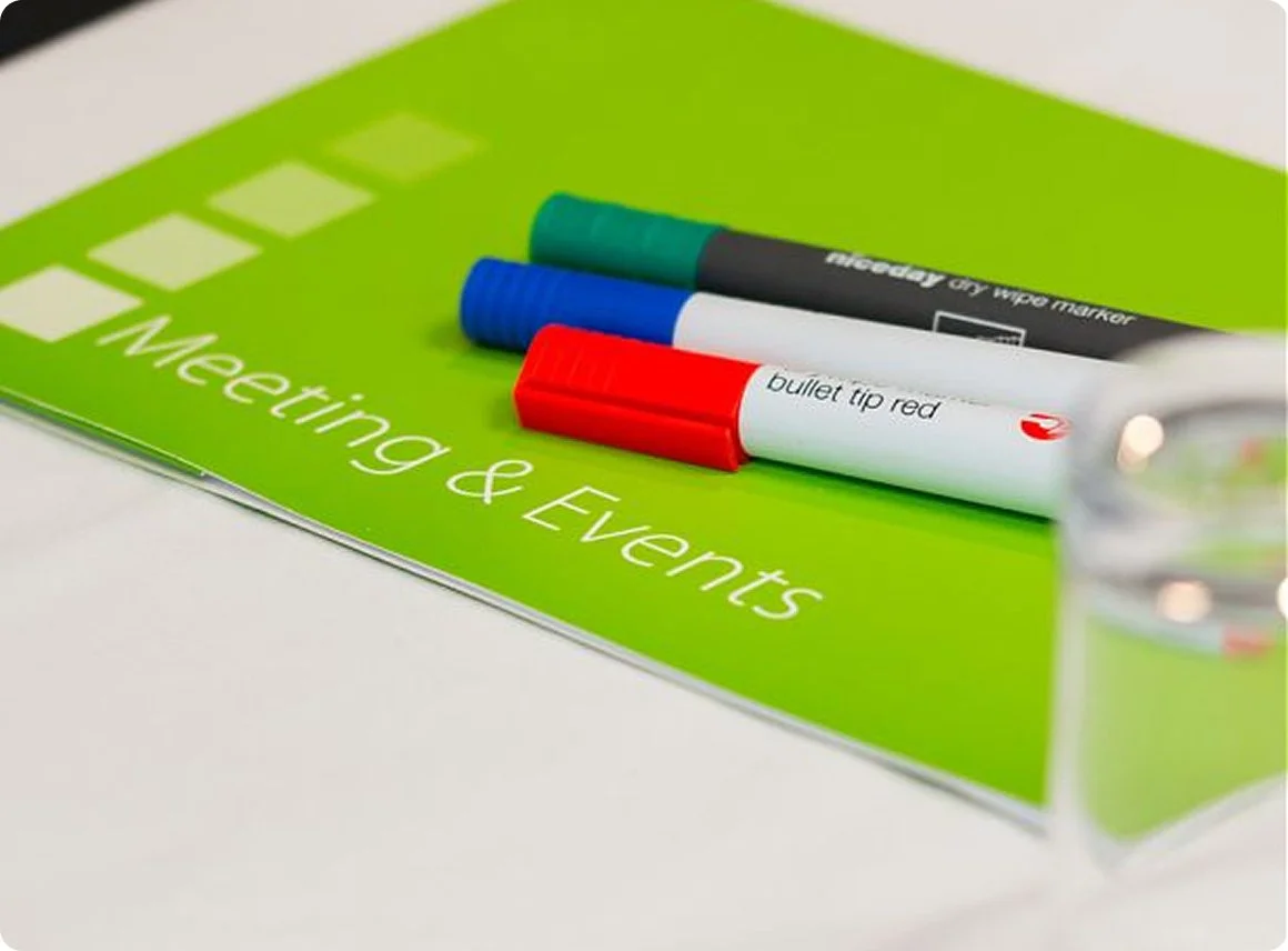 Green sign with white text that reads 'Meeting & Events,' with three markers on top: a teal, blue, and red marker.