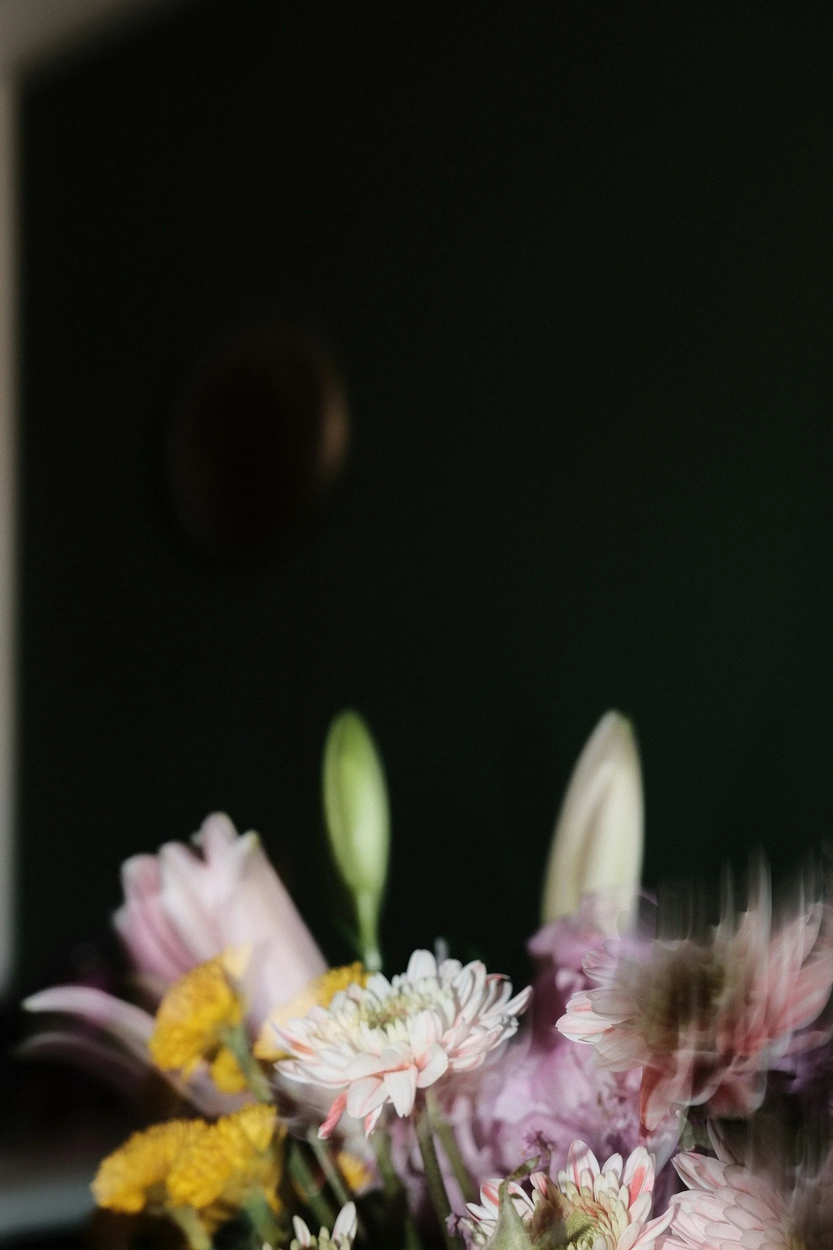 A bouquet of pink and yellow flowers against a dark background.